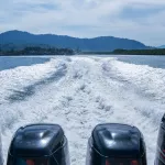Four Boat motors left a pass of foam on the water .